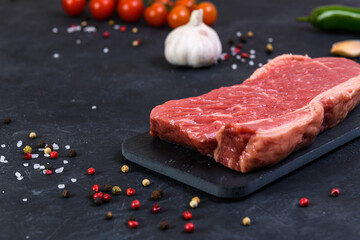 Raw fresh marbled meat and seasonings on dark background