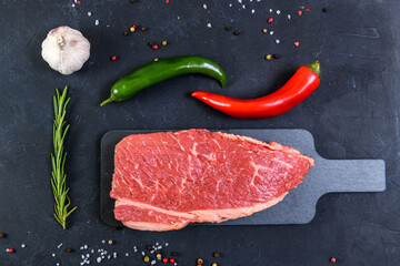 Raw fresh marbled meat and seasonings on dark background top view