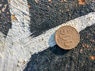 dirty 500 rupiah coins on the side of the road. top-down view