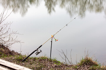 The fishing rod stands on the shore of the lake