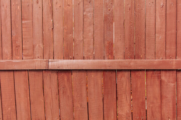 A wooden fence is painted with red paint as a background