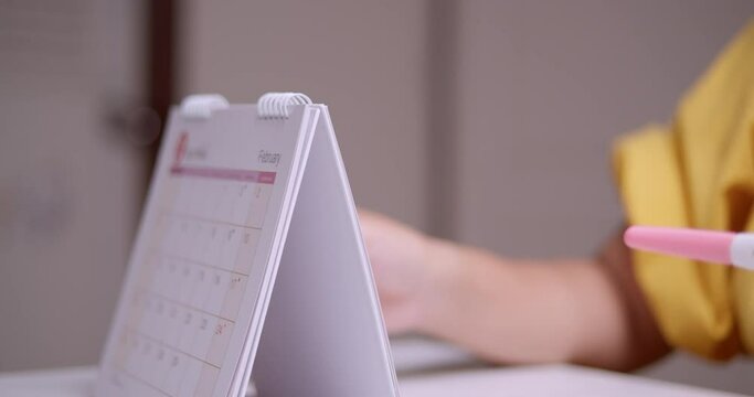 A pregnant woman browsing a calendar to count the days and months of her pregnancy to the date she is due to give birth.