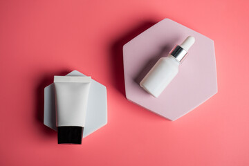 Plastic white tube for cream or lotion. Skin care or sunscreen cosmetic with stylish props on pink background.