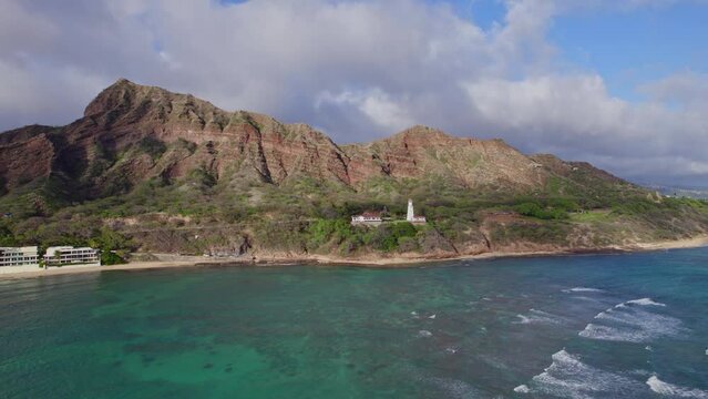aerial view of Diamond Head Lighthouse with Diamond Head mountain and clody sky with Turqoius clear water rolling to the shore