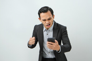 angry mad asian indonesian business man in suit holding smart phone on isolated background