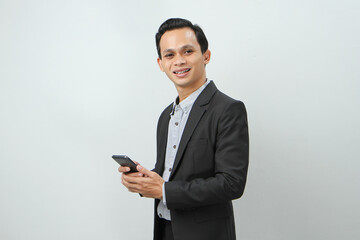 happy asian indonesian business man in suit holding smart phone on isolated background
