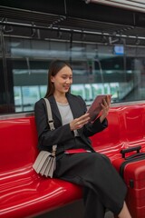 Young asian businesswoman traveling to airport on skytrain checking information using her digital tablet