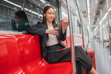 Young asian businesswoman traveling to airport on skytrain checking information using her digital tablet