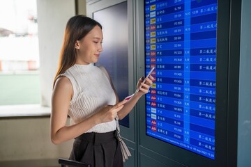 Young asian woman checking flight departure information at the airport
