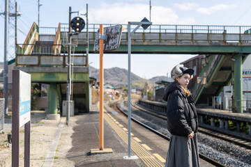 Fototapeta premium 田舎の駅のホームで電車を待つ女性