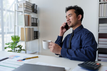 Businessman relaxes holding smartphone, checking email, work details on laptop computer online, contacting, business negotiation with customer pointing to successful business goals in office.