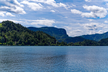 Fototapeta na wymiar Lake Bled with woodland and mountain panorama in the background on a cloudy summer day. Photo taken August 8th, 2023, Bled, Slovenia.