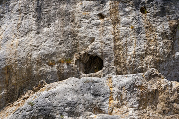 Close-up of cliff with hole and cave at lakeshore of Lake Bled on a cloudy summer day. Photo taken August 8th, 2023, Bled, Slovenia.