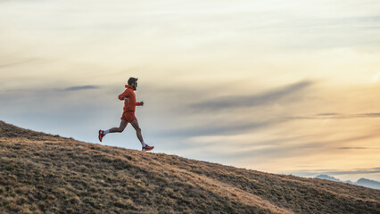 Sporty man runs in training on downhill meadow