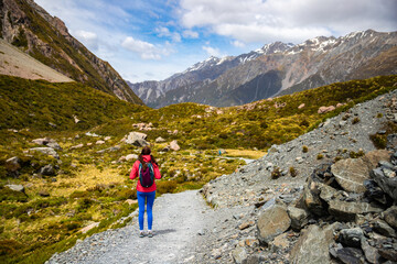hiker girl walking alongside hooker valley track toward hooker lake and mt cook, famous walk in...
