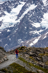 hiker girl walking alongside hooker valley track toward hooker lake and mt cook, famous walk in canterbury, new zealand south island