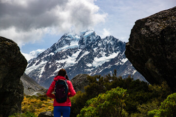 hiker girl walking alongside hooker valley track toward hooker lake and mt cook, famous walk in...