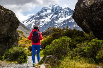 Photo sur Plexiglas Aoraki/Mount Cook hiker girl walking alongside hooker valley track toward hooker lake and mt cook, famous walk in canterbury, new zealand south island