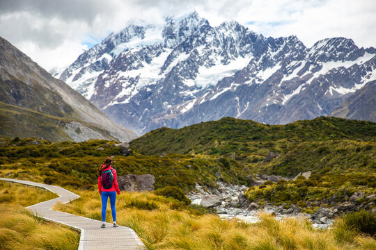 hiker girl walking alongside hooker valley track toward hooker lake and mt cook, famous walk in canterbury, new zealand south island