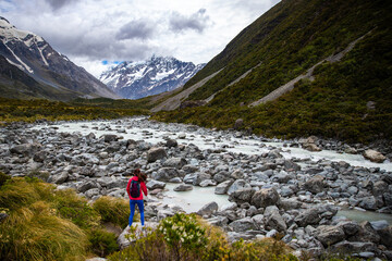 hiker girl walking alongside hooker valley track toward hooker lake and mt cook, famous walk in...