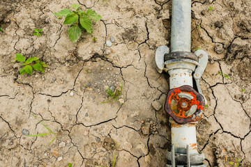 dried out soil with a turned off tap and only little plants due global warming