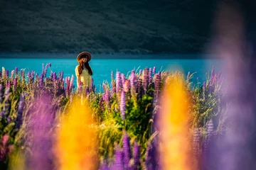 Papier Peint photo Aoraki/Mount Cook beautiful girl in yellow dress and hat standing on the field of colorful lupins and enjoying the sunset over lake tekapo  unique flowers near mountaineous lake in new zealand, south island, canterbury