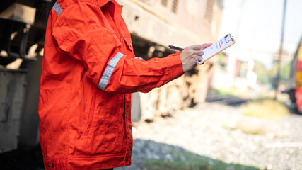 A service technician is checking on heavy machine maintenance checklist, with an ancient train...