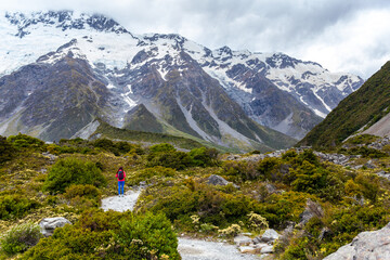 hiker girl walking alongside hooker valley track toward hooker lake and mt cook, famous walk in...