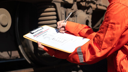 Action of a mechanic engineer is checking on heavy machine checklist form to verify the quality of...