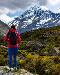 Fototapeta premium hiker girl walking alongside hooker valley track toward hooker lake and mt cook, famous walk in canterbury, new zealand south island