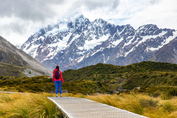 hiker girl walking alongside hooker valley track toward hooker lake and mt cook, famous walk in...