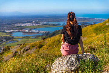 pretty girl sitting at the top of hill and watching the panorama of christchurch; hiking bridle...