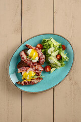Top view of a toast with crispy bacon and poached egg, served with a fresh green salad and a cup of espresso