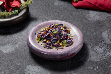Obraz na płótnie Canvas Black dumplings or ravioli with seafood and caviar in an elegant style, aesthetically pleasing winter menu