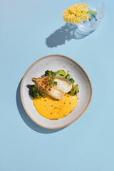 Halibut steak with pumpkin puree and broccoli, ideal for a vibrant summer menu in a high-end eatery