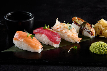 Classic nigiri sushi with salmon, tuna, eel, and shrimp on a black slate