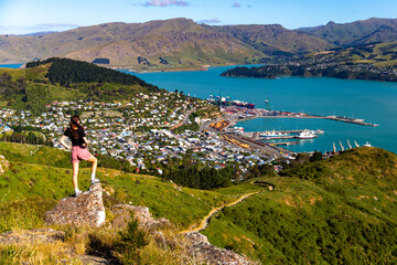 pretty hiker girl enjoying the panorama of lyttelton after finishing the hike on the bridle path from christchurch to lyttelton; beautiful view from gondola summit station, canterbury, new zealand 