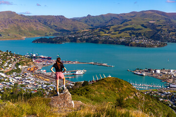 pretty hiker girl enjoying the panorama of lyttelton after finishing the hike on the bridle path from christchurch to lyttelton  beautiful view from gondola summit station, canterbury, new zealand  © Lens Down Under