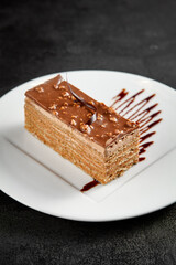 Gourmet hazelnut chocolate cake slice with nuts topping and artistic syrup drizzle on a white plate