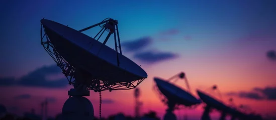 Foto auf Alu-Dibond Artistic decoration using selective focus on silhouetted satellite dishes or radio antennas against a night sky during sunset. © 2rogan