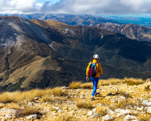 Obraz premium hiker girl walking down the steep trail from the top of mount somers in canterbury, new zealand south island