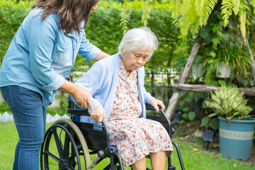 Caregiver help and care Asian senior woman patient sitting on wheelchair at nursing hospital ward,...