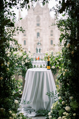Stack of glasses on a table next to a bottle of champagne on a balcony covered with roses overlooking the Duomo. Milan, Italy
