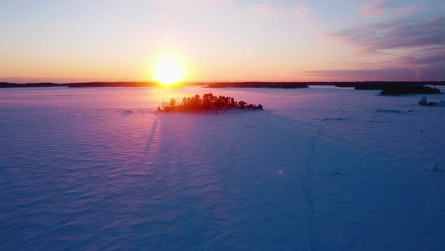 Drone shot over snowy ice and a isle, winter evening in the finnish archipelago