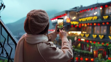 Young female tourist taking a photo of Jiufen old street landmark and popular attractions in Taiwan