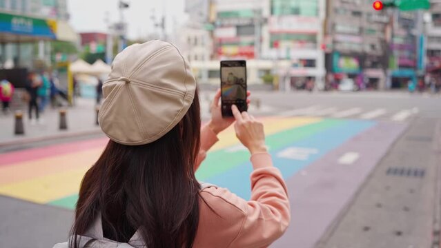 Young female tourist taking a photo of the Rainbow Road crossing at ximending in Taipei, Taiwan