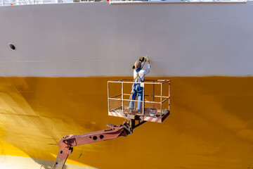 painting the bow of a big container ship inside dry dock