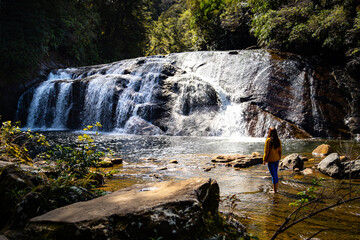 girl admires famous coal creek falls in new zealand, west coast of the south island near greymouth;...