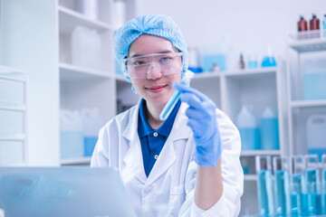 Closeup female woman scientist's hand holding blue liquid chemical chemistry test tube working in analyze science laboratory research experiment