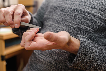 Man polishing nails to make them smooth after cutting, Personal touch: A man cares for his nails with precision and dedication, embodying self-grooming